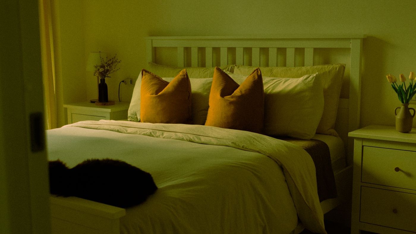 A bedroom with a made bed and warm bedside lighting