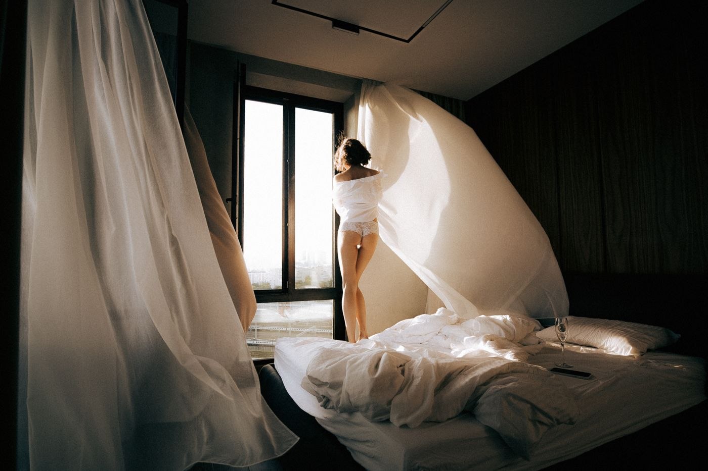 Woman Standing on the Bed by the Window