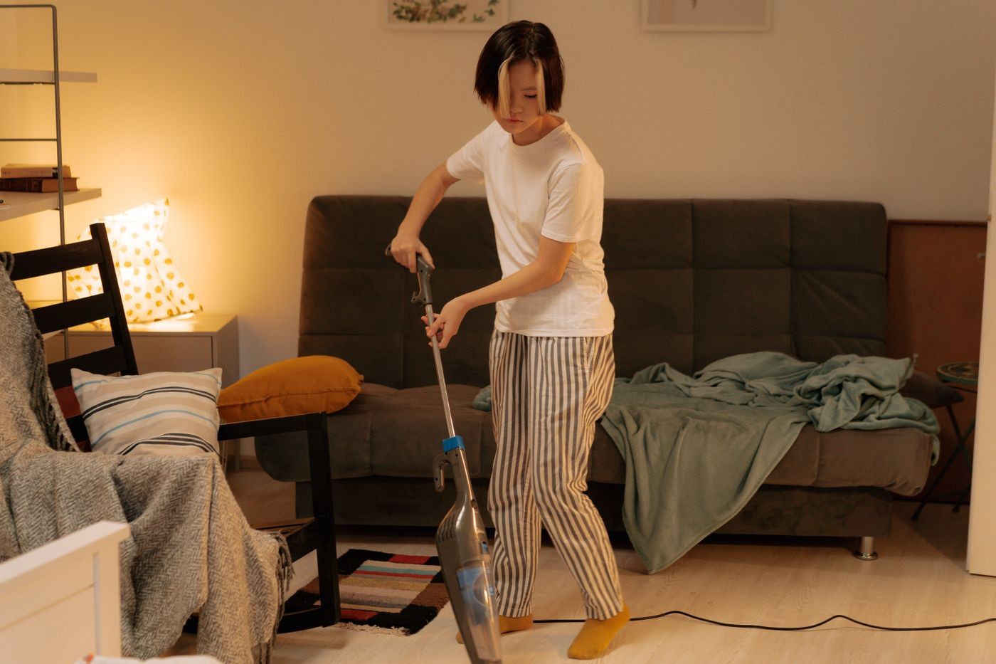 A person vacuuming the living room beside a sofa