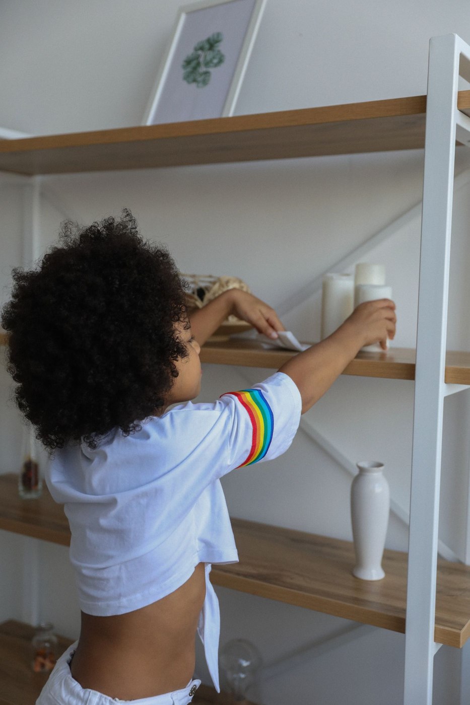 A child wiping a low shelf with a cloth