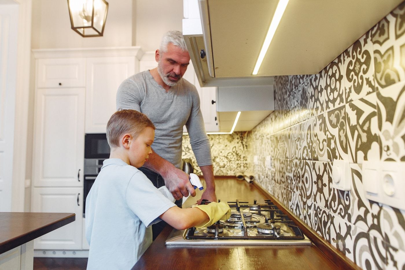 A parent and child washing dishes at the kitchen sink